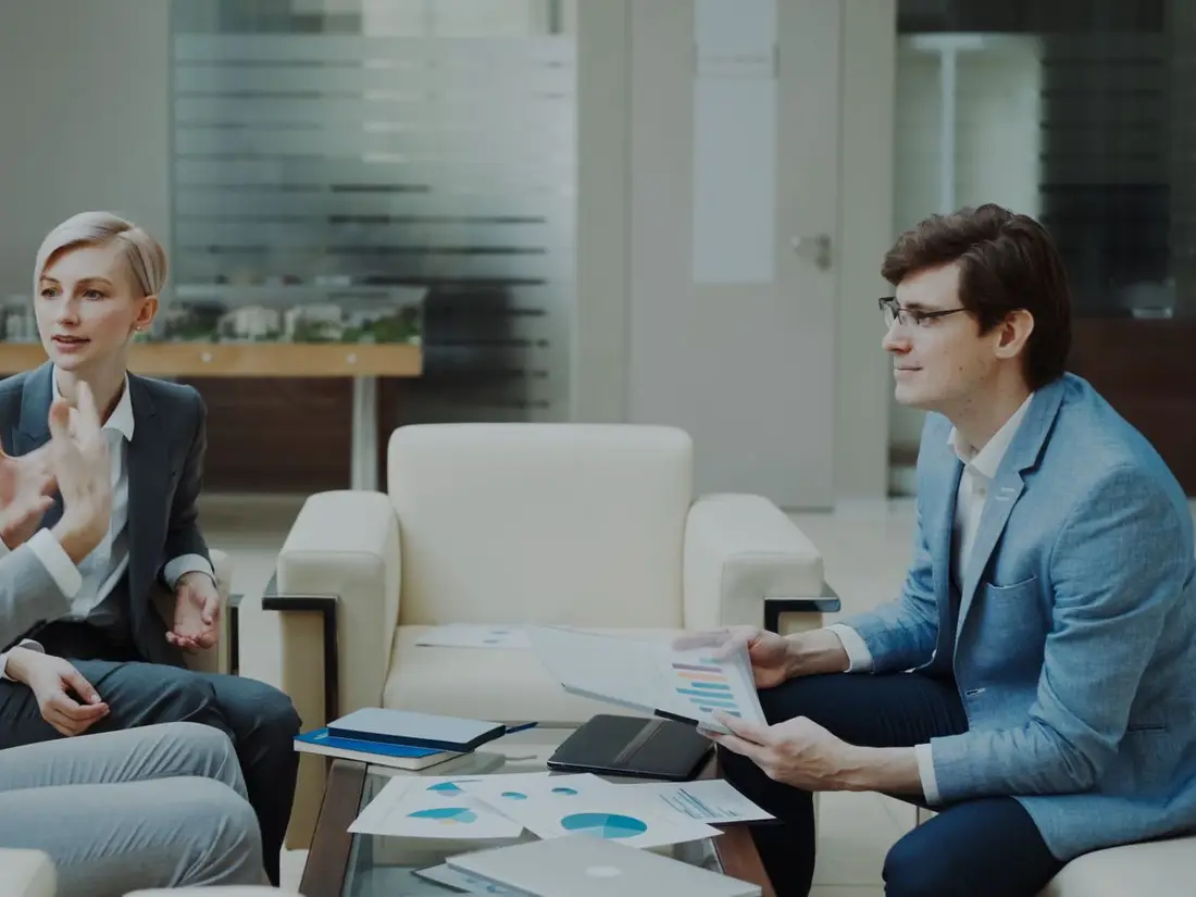 Three colleagues talking through financial charts in an office