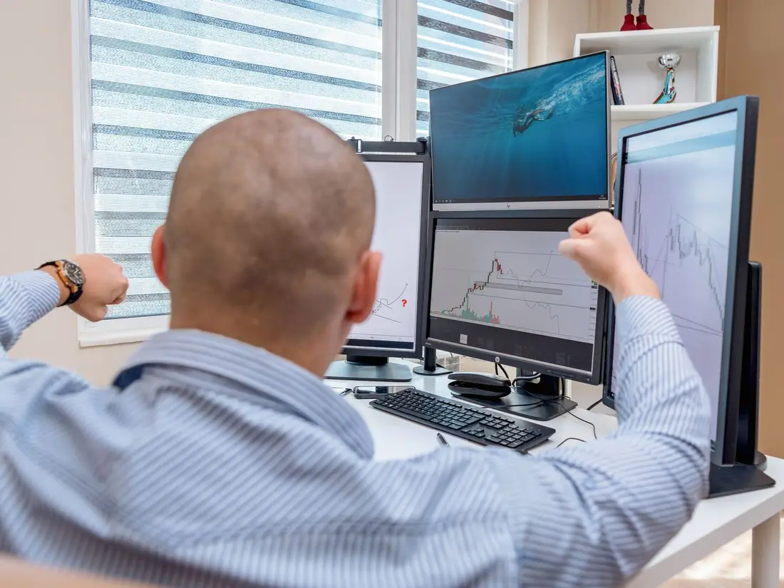 A trader at a desk watching several market screens